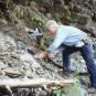 Colour photograph of man leaning down and picking rocks