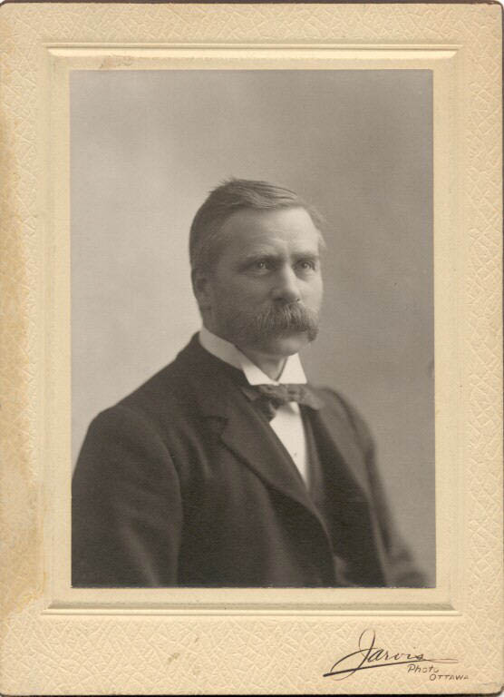 Photographie noir et blanc d'un homme portant complet et moustachu