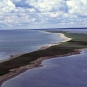 Photographie couleur d’une barre de sable couverte de végétation verdoyante, avec l’océan de part et d’autre