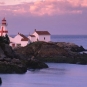 Photographie couleur d’un littoral rocheux, de l’océan et d’un phare rouge et blanc